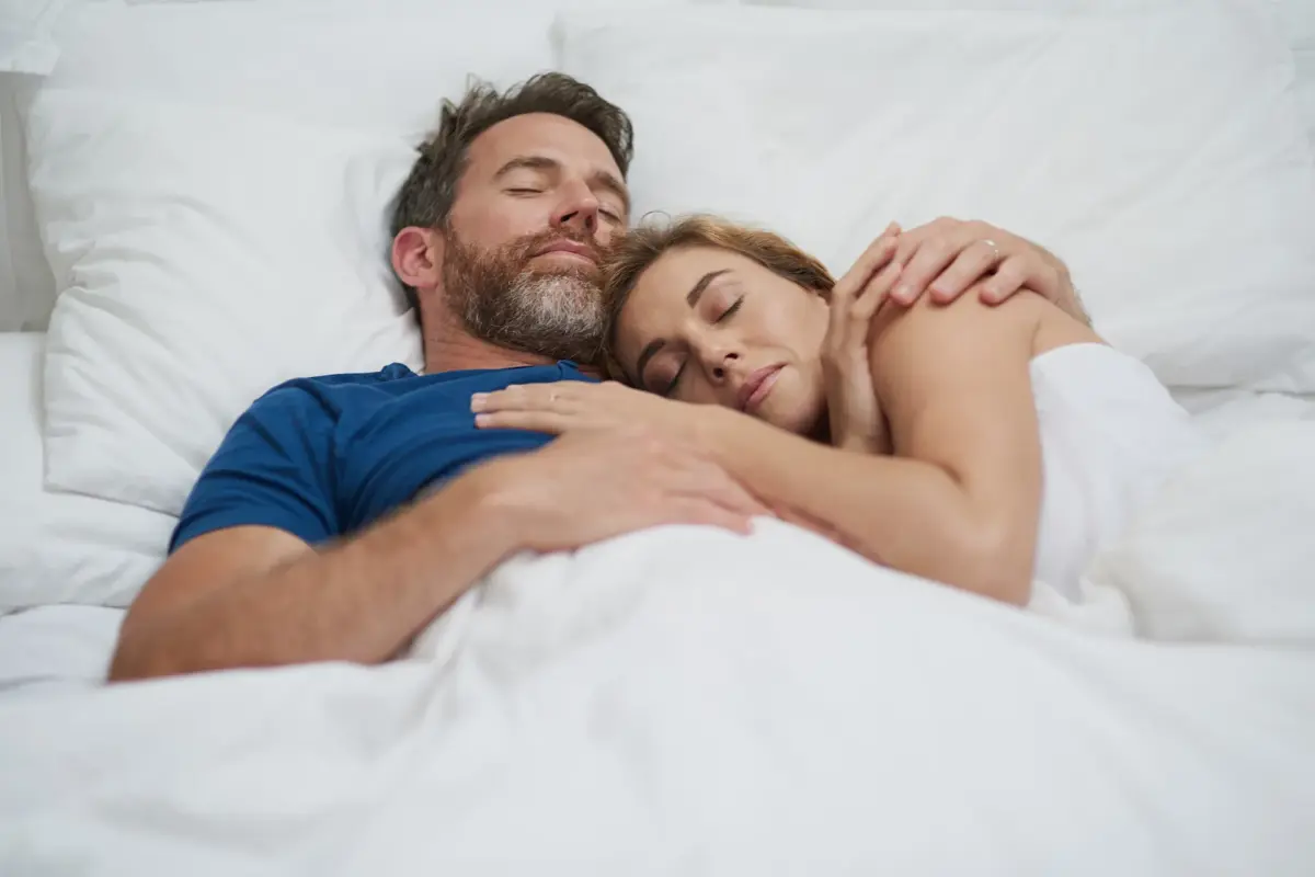 Paar liegt entspannt im Bett und schläft – besser einschlafen Tipps