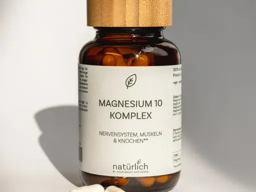 Magnesium 10 Komplex von natürlich by Dräxlmaier Apotheken – braune Dose mit weißem Etikett, Holzdeckel und zwei weißen Kapseln im Vordergrund