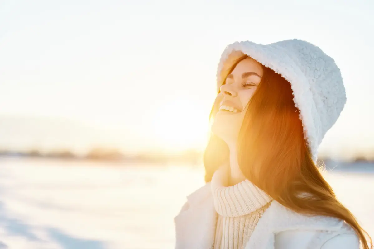 Frau genießt winterliche Sonne im Freien – Symbol für Vitamin D Winter