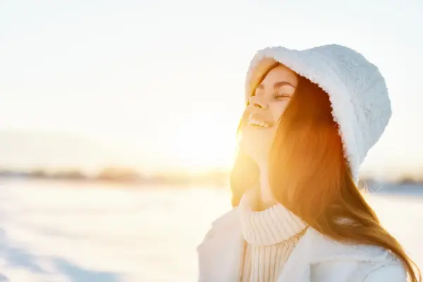 Frau genießt winterliche Sonne im Freien – Symbol für Vitamin D Winter