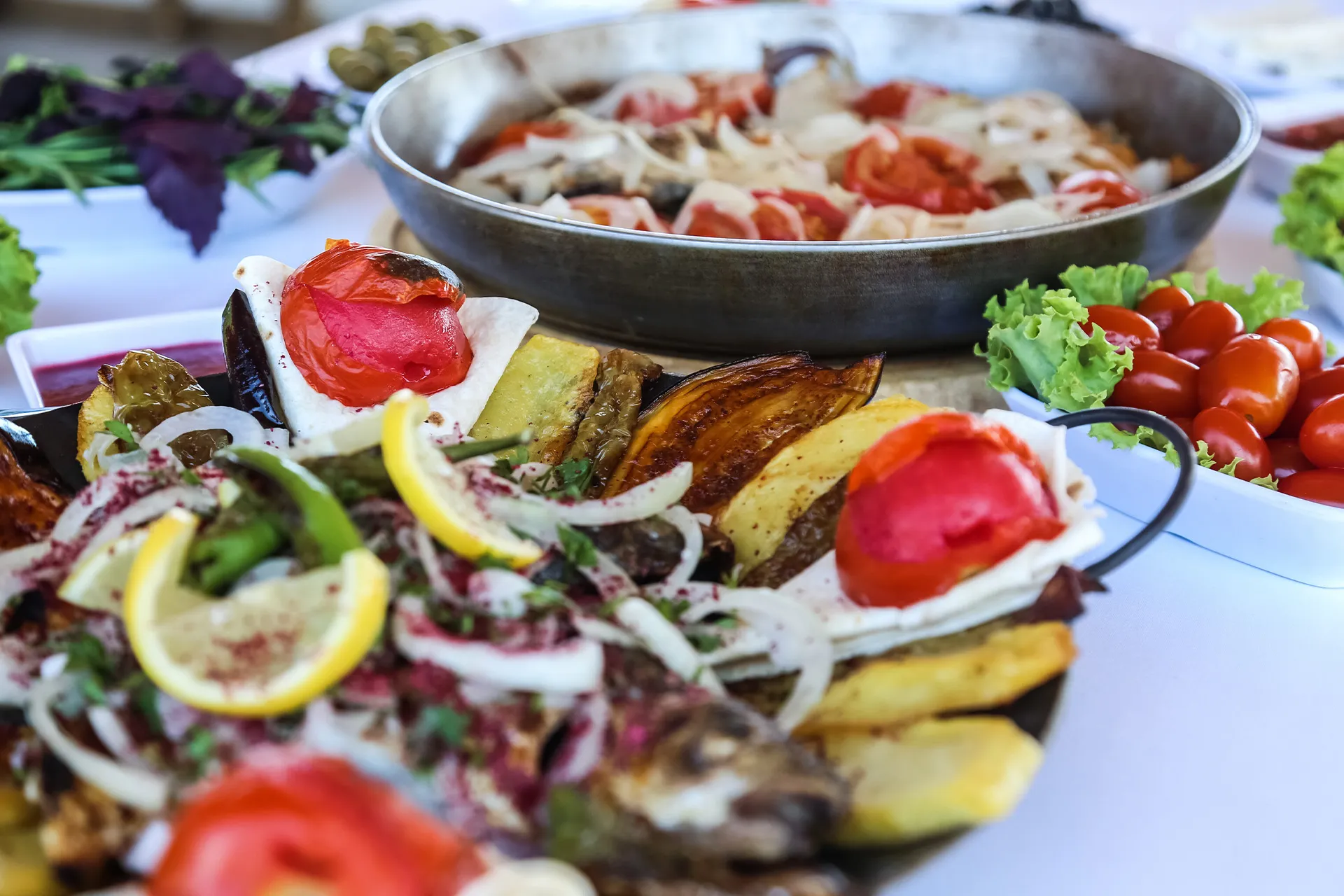 Mediterranes Urlaubsbuffet mit gegrilltem Gemüse, Auberginen, Tomaten, Kartoffeln, Zitrone und frischen Kräutern