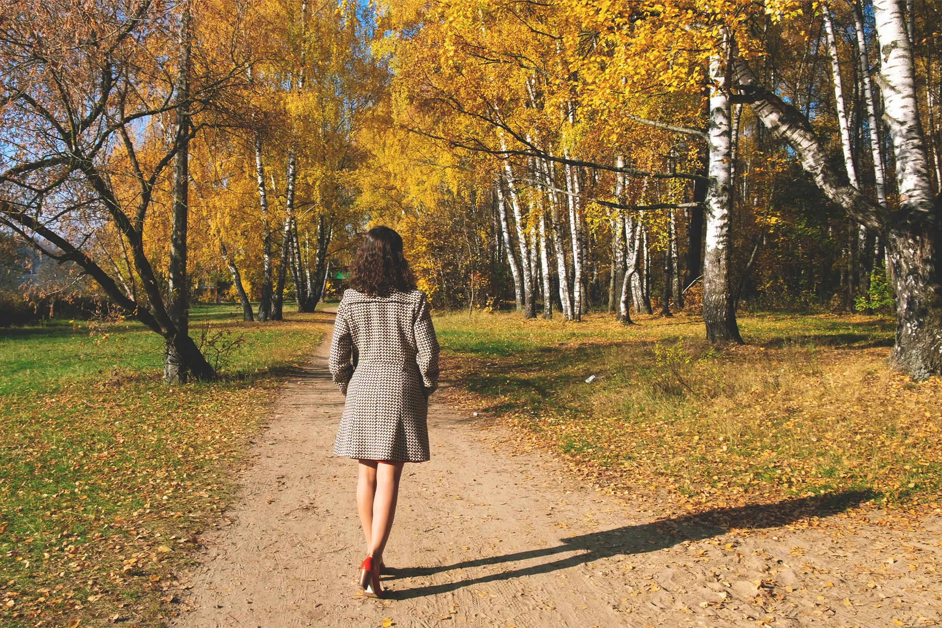 Frau beim Spaziergang im herbstlichen Park bei Tageslicht – wirksamste Routine gegen Herbstmüdigkeit